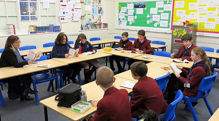 A group of students and a teacher reading together at lunchtime