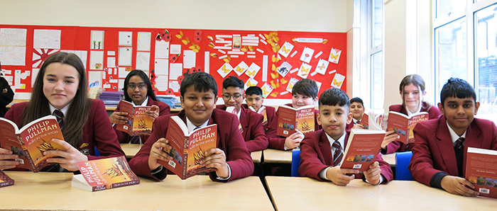 Yr 7 students sat at their desks with their reading books open and smiling